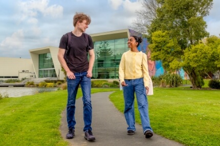 Male and female student walking outside in the college campus