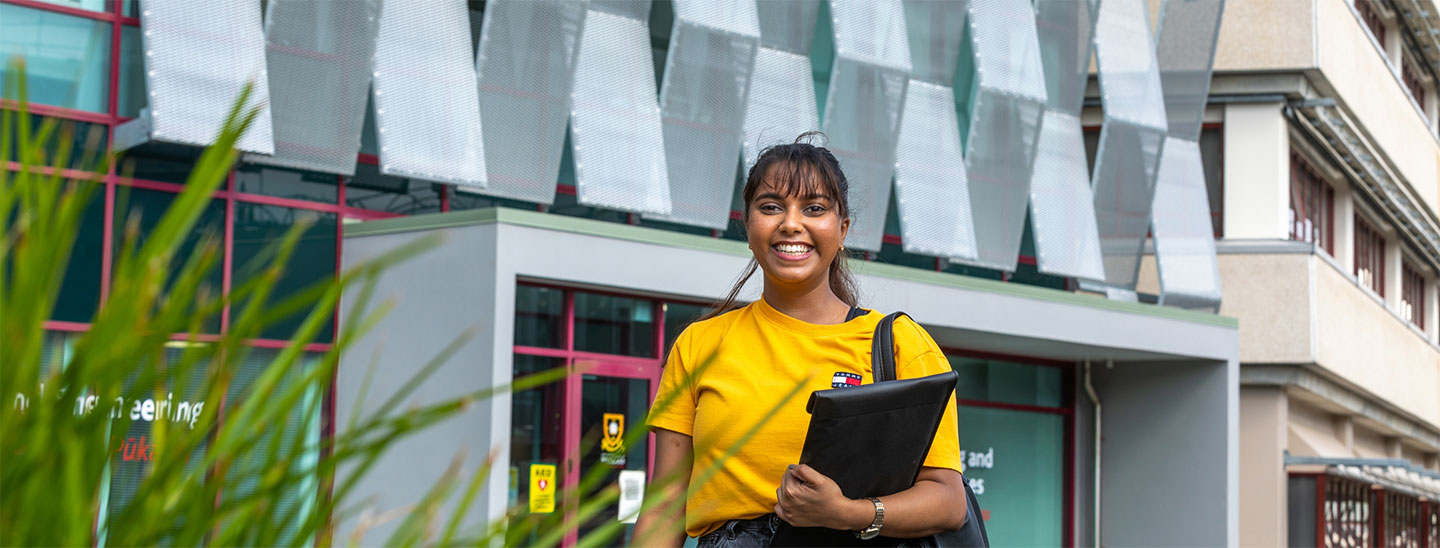 Student standing outside holding laptop