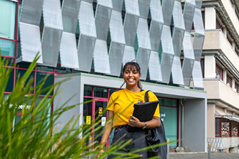 Student standing outside holding laptop