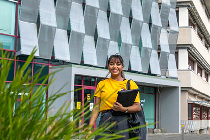 Student standing outside holding laptop