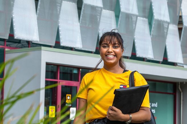 Student standing outside holding laptop