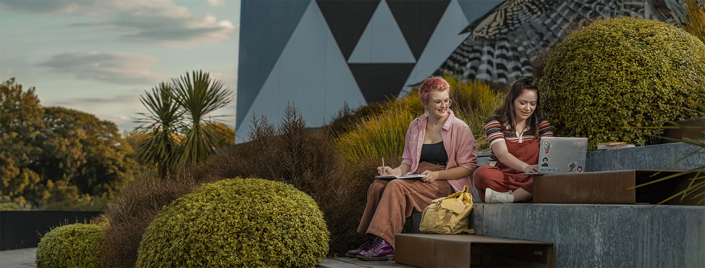 Students sitting outside working studying